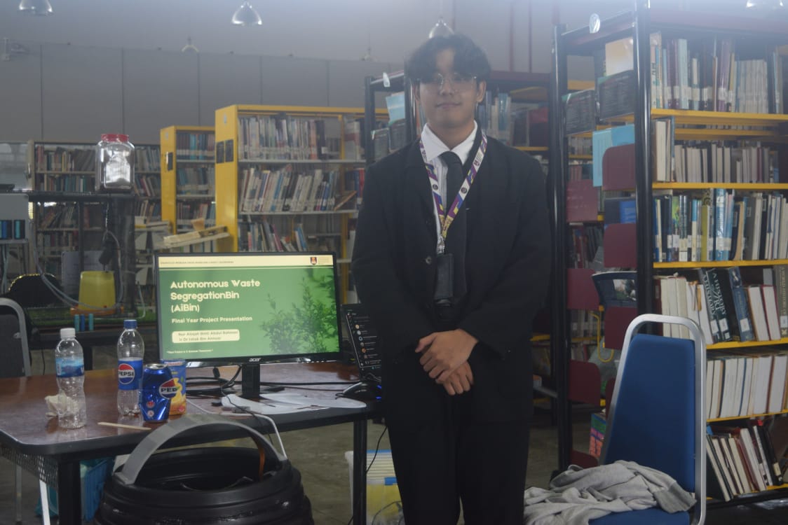 Anan standing beside the AiBin final year project presentation slide