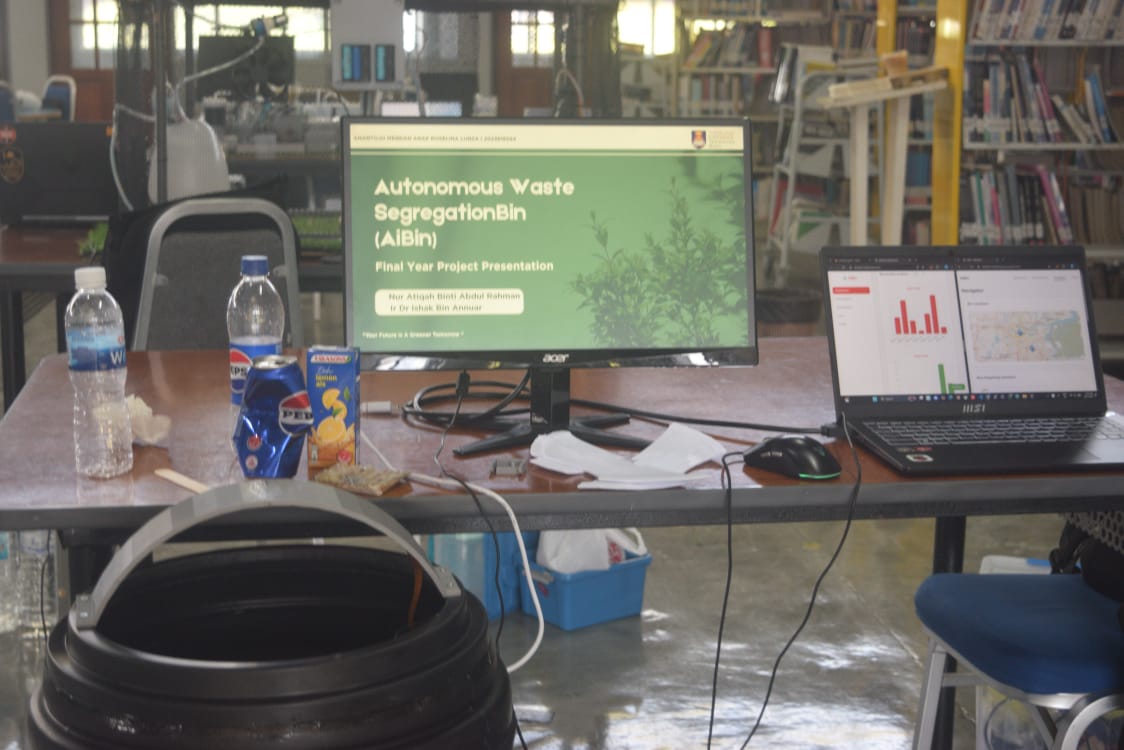 Full AiBin demo setup: presentation monitor, laptop showing analytics, and the physical bin